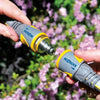 Two hands holding Hozelock garden nozzles against a blurred floral background