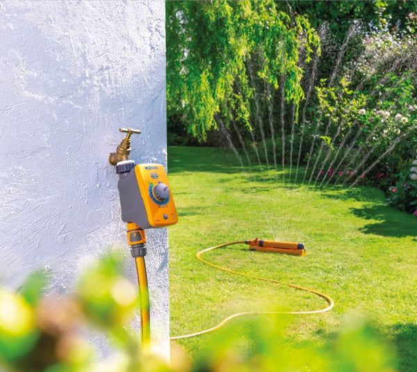 Hozelock Garden hose and sprinkler system with water spraying on a grassy area