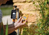 Person replacing irrigation timer batteries on a stone wall outdoors