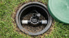 Outdoor sprinkler system valve on grass with green lid