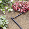 irrigation pipe on soil with plants and flowers in the background