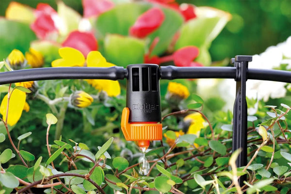 Claber Garden irrigation system with orange nozzle on a blurred garden background