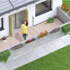 Woman standing on a deck with plants and flowers, next to a modern house. With a Claber Irrigation system in the backlground.