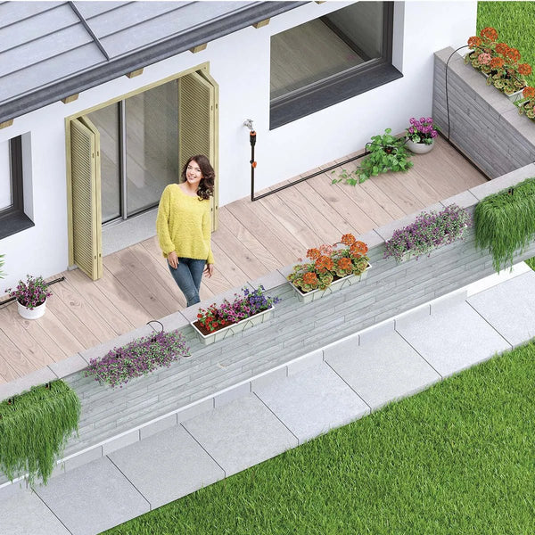 Woman standing on a deck with plants and flowers, next to a modern house. With a Claber Irrigation system in the backlground.