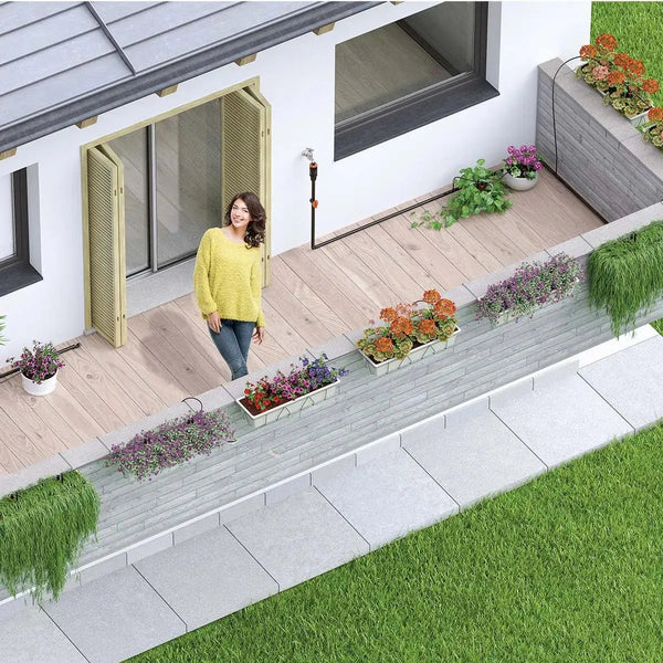 Woman standing on a deck with plants and flowers, next to a modern house. With a Claber Irrigation system in the backlground.