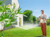 Person using a smartphone while standing in a garden with a sprinkler system