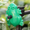 Green frog-shaped garden sprinkler with a blurred green background