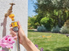 Hozelock 2070 garden hose with a nozzle, with a garden and flowers in the background.
