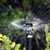 Sprinkler spraying water in a garden with greenery