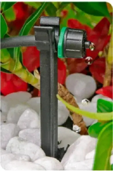 Close-up of a garden irrigation system with plants and stones in the background