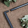 Black garden irrigation pipes on soil with plants around