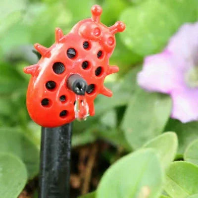 Red ladybug-shaped sprinkler head on a green leafy background