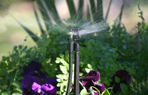 Garden sprinkler in action with plants and flowers in the background