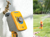 Hozelock garden hose pressure regulator attached to a wall with a garden sprinkler in the background.
