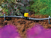Garden irrigation system with a yellow valve in a garden setting