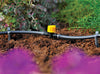 Garden irrigation system with a yellow valve in a garden setting