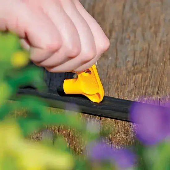 Using a yellow tool on a wooden surface with blurred flowers in the foreground
