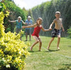 Children playing with a garden hose in a sunny backyard