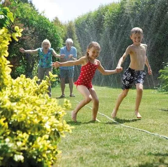Children playing with a garden hose in a sunny backyard