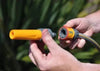 Person holding two garden hose nozzles against a blurred green background