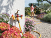 Hose and nozzle with flowers and a person watering plants in a garden.
