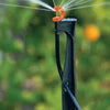 Sprinkler head with water spray against a blurred green background