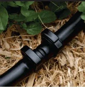 Irrigation hose clips securing connector over bark flowerbed