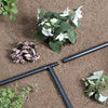 Black garden irrigation system components on a soil background with plants.