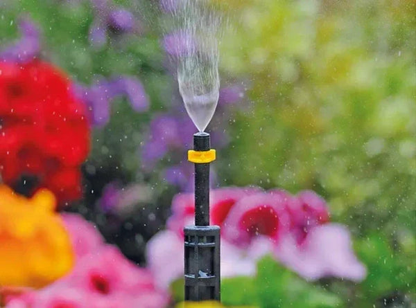 Garden irrigation mister with colorful flowers in the background