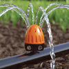 Claber Orange and black sprinkler spraying water in a garden setting