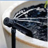 Sprinkler head attached to a hose, spraying water into a pot with soil.