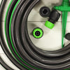 Coiled garden irrigation hose with green connectors and spray nozzle on light wood