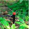Garden sprinkler spraying water on green plants with a blurred green background