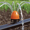 Claber Orange and black sprinkler spraying water in a garden setting